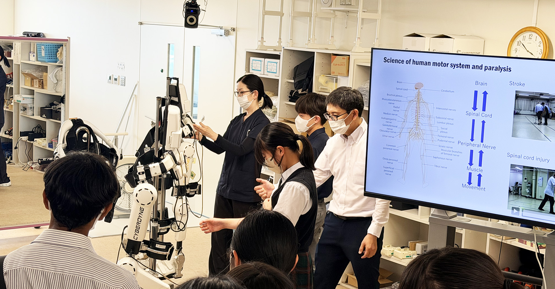 学生の方が腕にセンサーを装着し、HALの動きを体験している様子